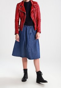Red leather biker jacket, black sweater, knee-length denim skirt, and black lace-up boots. Smooth texture, fitted design, casual style.