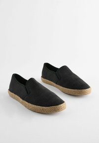 Zwarte instap espadrilles met een visgraatpatroon, bovenwerk van geweven stof en een natuurlijke jute touwzool. Soepel textuur, casual ontwerp.
