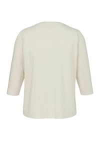Helles Beige, 3/4-Arm-Oberteil aus weichem Stoff. Verfügt über einen runden Halsausschnitt und eine lockere Passform. Glatte Textur ohne sichtbare Muster oder Akzente.