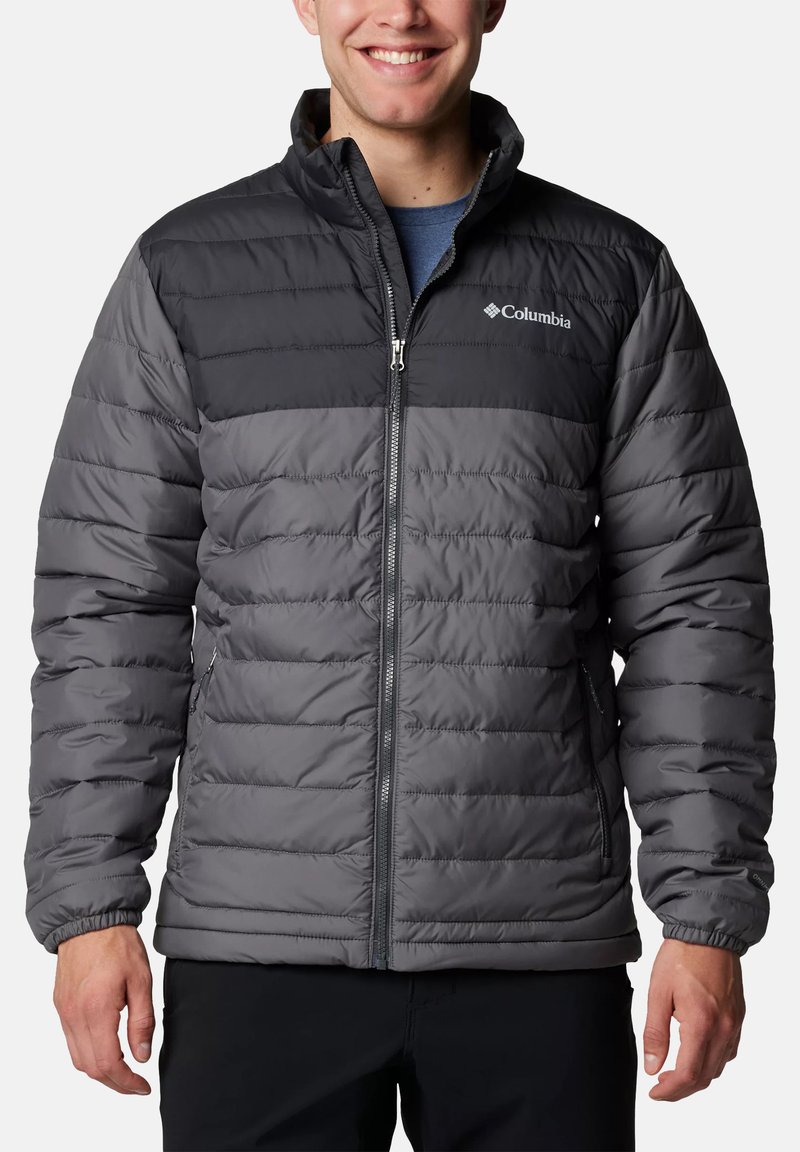 Herren Columbia Pufferjacke mit schwarzem Oberteil und grauem, gestepptem Unterteil, bestehend aus isoliertem Material und mit Reißverschlusstaschen.