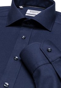 Navy blauwe slim-fit overhemden met een puntkraag, donkere knopen en een soepel textiel met een opgerolde manchetdetail.