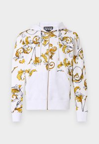 White zip-up hoodie with yellow and black decorative swirl patterns, front pockets, and drawstrings at the hood. Soft fabric texture.