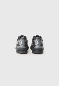 Black athletic shoes featuring a textured mesh upper, reflective accents, and a cushioned sole with a similar dark color scheme.