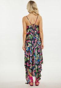 Rochie maxi cu tiv înalt și jos, imprimată vibrant cu motive paisley în nuanțe de roz, verde și albastru, cu bretele spaghetti ajustabile și detaliu legat la spate.
