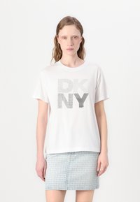Balta trumpo rankovės marškinėliai su tekstūruotomis sidabro spalvos raidėmis "DKNY", kombinuojami su raštuota šviesiai mėlyna sijonu.