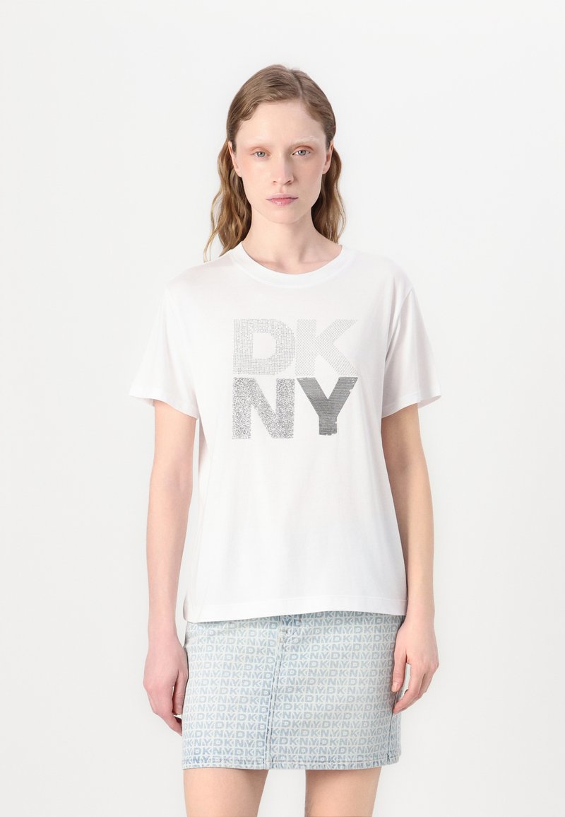 Balta trumpo rankovės marškinėliai su tekstūruotomis sidabro spalvos raidėmis "DKNY", kombinuojami su raštuota šviesiai mėlyna sijonu.