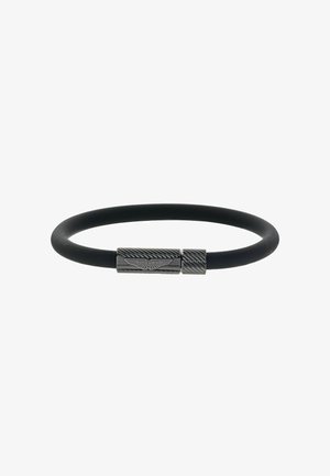 Pulsera de goma negra con cierre metálico que presenta un patrón texturizado y un detalle de logotipo en relieve. Diseño elegante y minimalista.