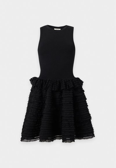 Robe noire sans manches avec un haut ajusté et une jupe texturée à volants, présentée sur un fond clair uni.