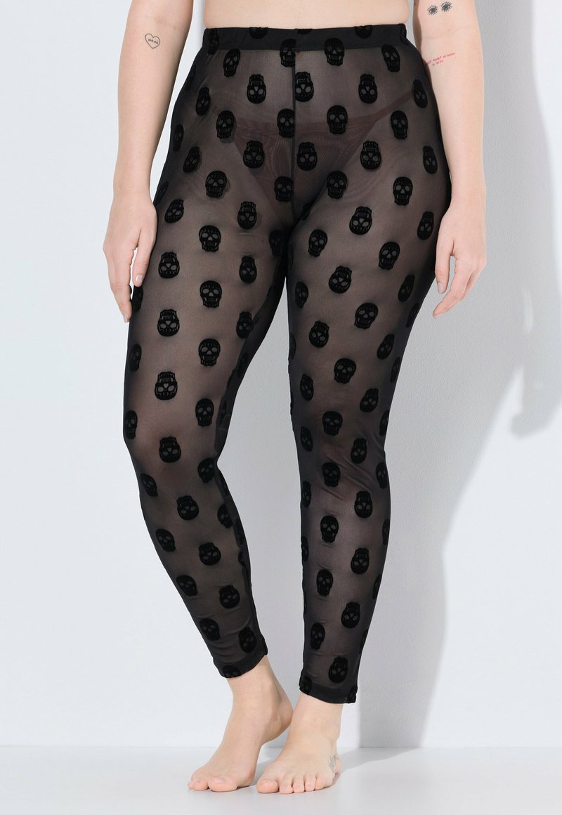 Leggings neri trasparenti con un motivo di teschi ripetuto. Il materiale è leggero e semi-trasparente, con un design aderente.