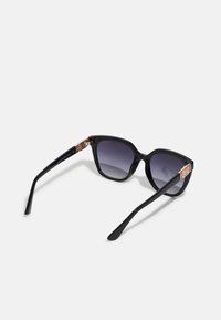 Black plastic sunglasses with gray gradient lenses, featuring a gold-tone accent on the temple and sleek, angular design.