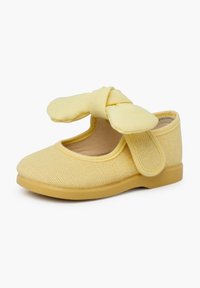 Kollane kangast king, millel on tekstuuriga pind, ümar varvas ja suur paeltehnikaga detail rihmal. Vastupidav kummist tall, mis tagab haarde.