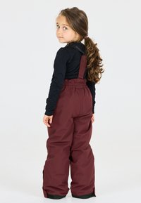 Pantaloni da neve color bordeaux con spalline regolabili, vita elastica e dettagli neri. Tessuto liscio e design morbido per il massimo comfort.