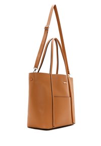 Tan leren totebag met dubbele handvaten en een verstelbare schouderband. Voorzien van een voorvak en minimalistische gouden branding.