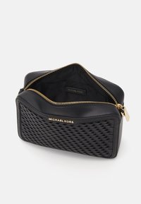 Funda de cuero negro con textura tejida en la parte frontal, cremallera dorada y logo de "Michael Kors" en el exterior e interior.