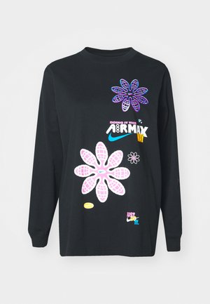 Must svart pika, millel on värvikad lilleteemalised graafikat ja tekst, sealhulgas "TEEME SEDA AIRMAXI MOODI" ja "LIHTSALT TEEN SEE."