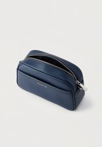 Kozmetična torbica iz mornarsko modrega usnja z teksturirano površino, dvojno zadrgo in sprednjim žepom. Ima srebreno kovinsko opremo in logotip.