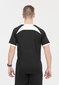 Svart idrottströja med vita detaljer på axlarna och ärmkanterna. Tillverkad av lättviktsmaterial, med en lös passform och rund halsringning.