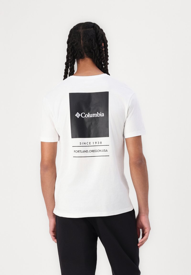Hvit bomulls t-skjorte med et stort svart boksdesign på baksiden med "Columbia"-logo og tekst "SINCE 1938 PORTLAND, OREGON, USA."