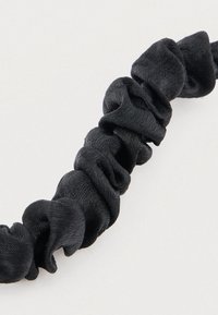 Μαύρο σατέν scrunchie με υφασμάτινο, ρυτιδωτό σχέδιο. Διαθέτει λεία επιφάνεια και ελαστικό λουράκι για σταθερό κράτημα.