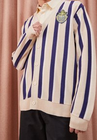 Cremfarbener und marineblauer Streifen-Cardigan mit V-Ausschnitt, Knopfverschluss und strukturiertem Strick. Enthält ein gesticktes Patch in Grün und Blau.