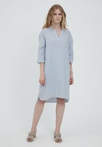 Ljusblå linnklänning med V-ringning, trekvartsärmar och sidslitsar. Kombinerad med beige klacksandaler med volangdetaljer.