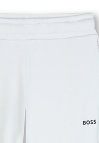 Witte sweatpants met een gestructureerde afwerking, voorzien van een trekkoord in de taille en een zwart "BOSS" logo aan de onderzijde links.
