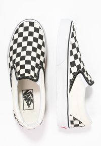 Sorte og hvite rutete slip-on sneakers med en hvit gummisåle og elastiske sideakenter. Innvendig har den en polstret såleinsole.