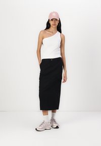 Haut blanc à une épaule, jupe noire jusqu'aux genoux avec poches latérales, casquette de baseball rose et baskets grises claires avec chaussettes blanches.