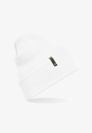 White ribbed knit beanie with a folded cuff and a small black tag featuring a star emblem. Soft texture with a snug fit.
