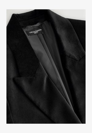 Must mustrida puhuljak, mis sisaldab nurgelist kraed, elegantselt sirgeid klappe ja siledat satiinvoodrit. Peen tekstuur minimaalsete õmblusdetailidega.