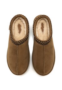 Zapatillas de ante marrón con un suave forro de piel sintética, que presentan un borde decorativo cosido en patrones oscuros y claros alrededor de la abertura.