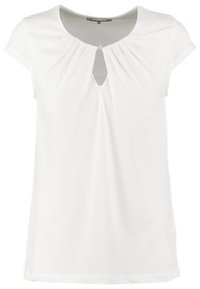 Haut blanc à manches courtes avec un col arrondi, présentant une découpe en forme de trou de serrure à l'avant, et de légers plis pour la texture. Tissu lisse.