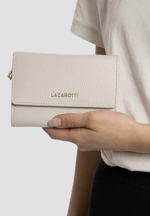 Billetera de cuero gris claro con acabado texturizado, que presenta un diseño de solapa y una marca en dorado. Sostenida a mano frente a un fondo neutro.