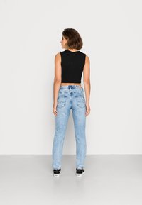 Top cropped preto combinado com jeans retos azul-claro. Os jeans apresentam um design clássico com bolsos traseiros e um mínimo desgaste.