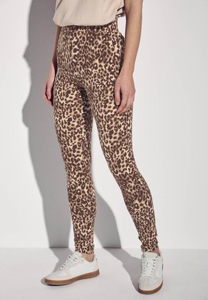 Leggings a stampa leopardata in tonalità beige e marrone, design a vita alta, tessuto elasticizzato, abbinati a sneakers bianche e beige, texture morbida.