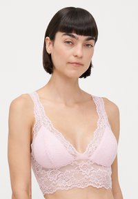 Rosa blonde bralette med trekantet form, brede blonde stropper og blomstermønster, med en myk, teksturert finish og elastisk bånd.
