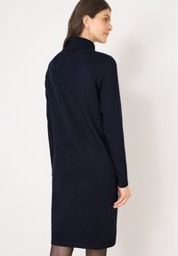 Abito in maglia blu navy con maniche lunghe, colletto alto e silhouette aderente. Design semplice con una trama liscia e senza pattern visibili.