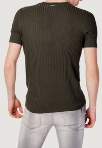 Maglione corto a maniche corte di un verde scuro a coste con scollatura rotonda, caratterizzato da un tessuto strutturato e una silhouette aderente. La vista posteriore mostra dettagli delle cuciture.