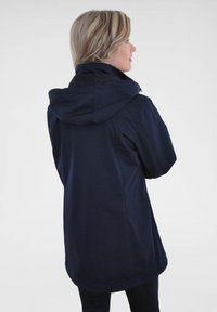 Marineblaue wasserdichte Jacke mit Kapuze, die über eine glatte Textur, verstellbare Manschetten und einen leicht taillierten Schnitt verfügt.