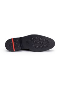 Zwarte zool van de schoen met een getextureerde rubberen oppervlakte, voorzien van afgeronde noppen voor grip en een rode accentstreep. Gladde oppervlakte met een duurzame constructie.