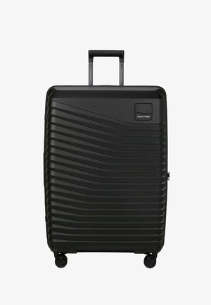 Valise rigide noire avec motifs en vagues horizontales, quatre roulettes, poignée extensible et logo Samsonite en haut à droite.
