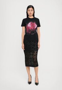 Black cotton t-shirt with a pink artistic graphic, paired with a black lace pencil skirt featuring floral patterns. Black high-heeled shoes.