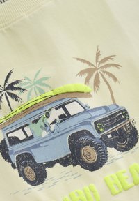 Lys gul stof har et grafisk motiv af en blå SUV med et surfbræt, omgivet af palmetræer, og "STRAND" i lys grøn skrift.