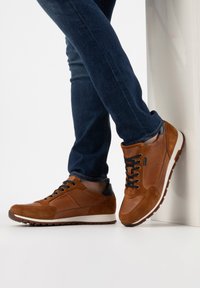 Sneaker marroni realizzati in suede e pelle, caratterizzati da un design testurizzato, accenti neri, lacci rotondi e una suola bianca con un motivo antiscivolo.