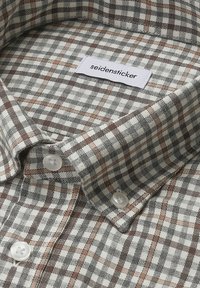 Koszula w kratę w kolorach szarym, białym i brązowym; posiada kołnierz zapinany na guziki, plastikowe guziki oraz metkę z napisem "seidensticker" na wewnętrznej stronie kołnierza.