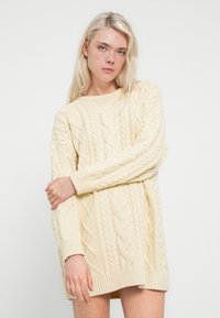 Πλεκτό πουλόβερ σε κρεμ χρώμα με σχέδια πλεξίματος καναλιού, μακριά μανίκια και άνετη εφαρμογή με ριμπ μανσέτες και τελείωμα.