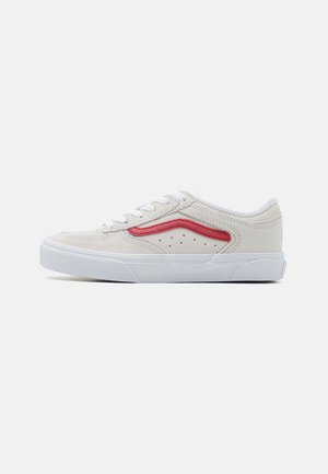 Zapatillas de ante blancas con una franja lateral roja, que presentan perforaciones y una suela texturizada. Cierre de cordones en la parte frontal y cuello acolchado para mayor comodidad.