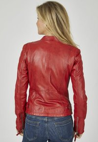 Rote Lederjacke mit schmalem Schnitt, Nahtdetails und Reißverschlussärmeln, kombiniert mit blauen Jeans. Schlichte, glatte Textur.