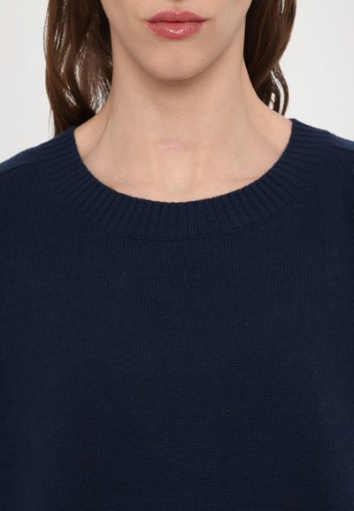 Navy blue knitted sweater featuring a ribbed crew neckline and smooth texture, focusing on the upper chest and neckline area.