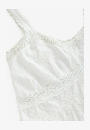 Weißes Kleid mit Spitze und floralen Stickereien. Verfügt über gewellte Träger und einen geschichteten Textur, die die komplizierten Details hervorhebt.